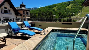 A pool area with lounge chairs and a view of a mountain.