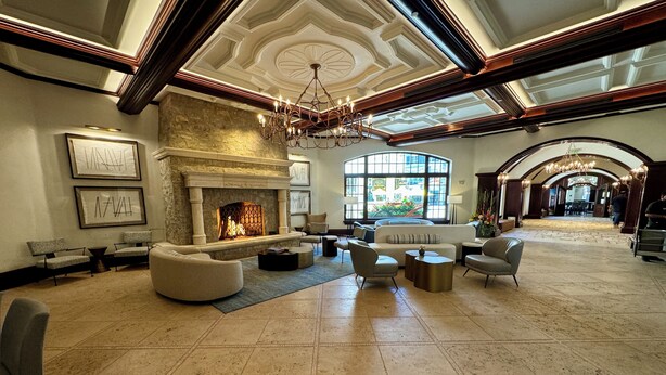 A spacious lobby with a fireplace, comfortable seating, and a large window offering a view of the outdoors.