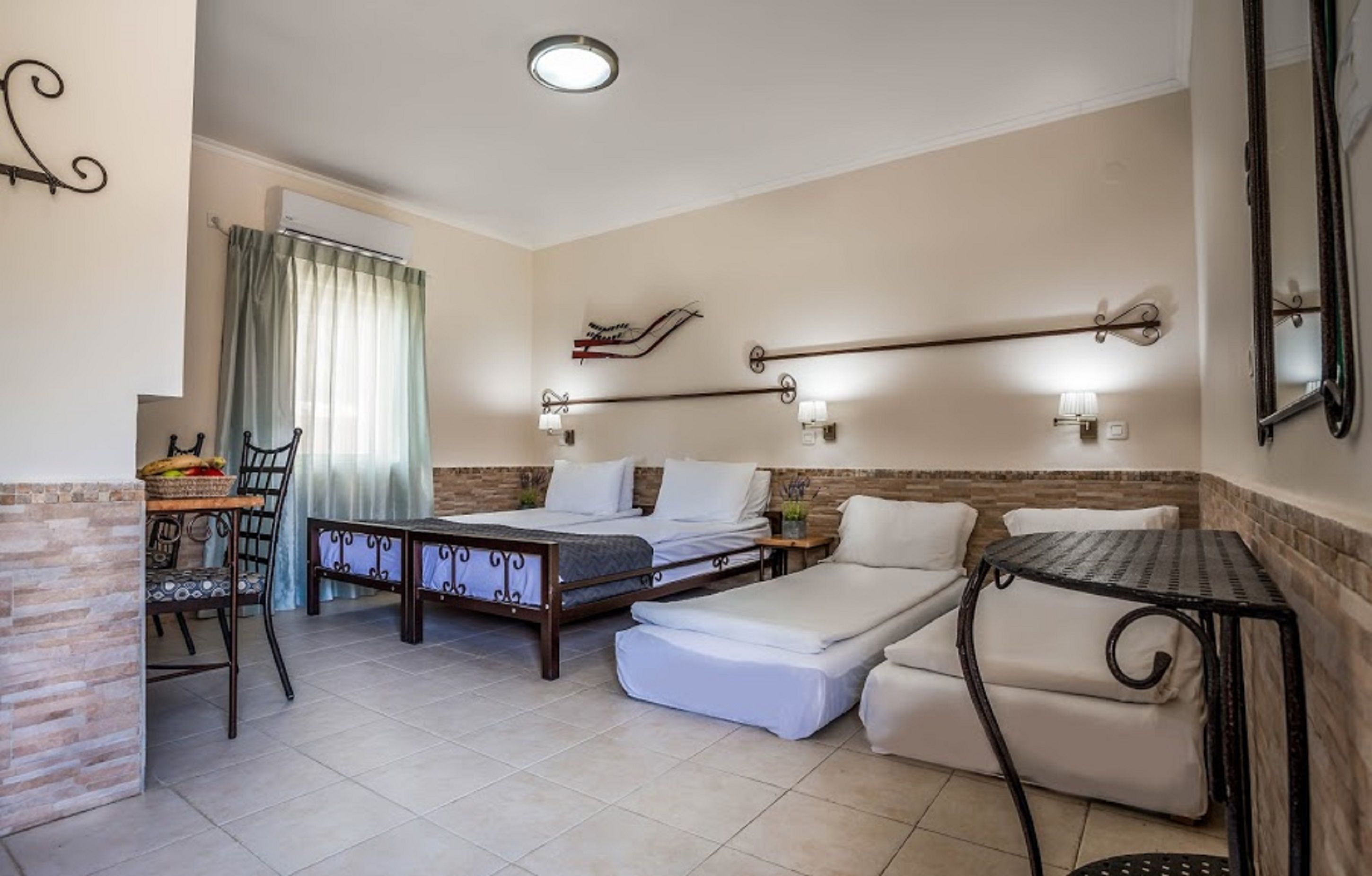 Un dormitorio con cama, sofá, una mesita, una silla y una ventana con cortinas.