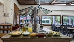 Montaje de bufé con diversos alimentos y un dispensador de bebidas.