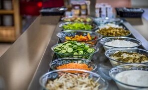 A buffet line with various food items including sliced cucumbers, carrots, and other vegetables. - Kibbutz Mashabei Sade Country Lodging (Ramat Negev)