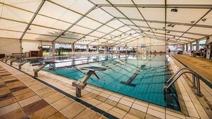 Una piscina interior con suelo de baldosas y una cubierta superior.