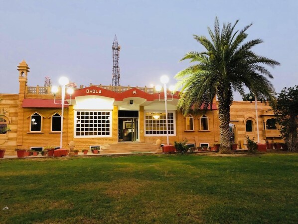 A hotel with a traditional architectural style, featuring a prominent entrance with a red awning and the name 'DHOLA' displayed above.