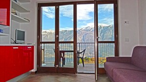 A room with a sliding glass door leading to a balcony with a mountain view. - La Quiete 56 Holideal (Tremosine)