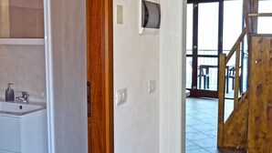 A bathroom with a shower, a toilet, and a sink. There is a wooden door frame and a window with a view of the outside. - La Quiete 56 Holideal (Tremosine)