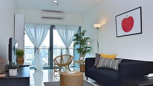 A modern living room with a black sofa, a wicker ottoman, a chair, a small table, and a framed picture on the wall. - S1 Awesome 1BR near KLCC - KL Tower - Hi Speed WIFI (Kuala Lumpur)