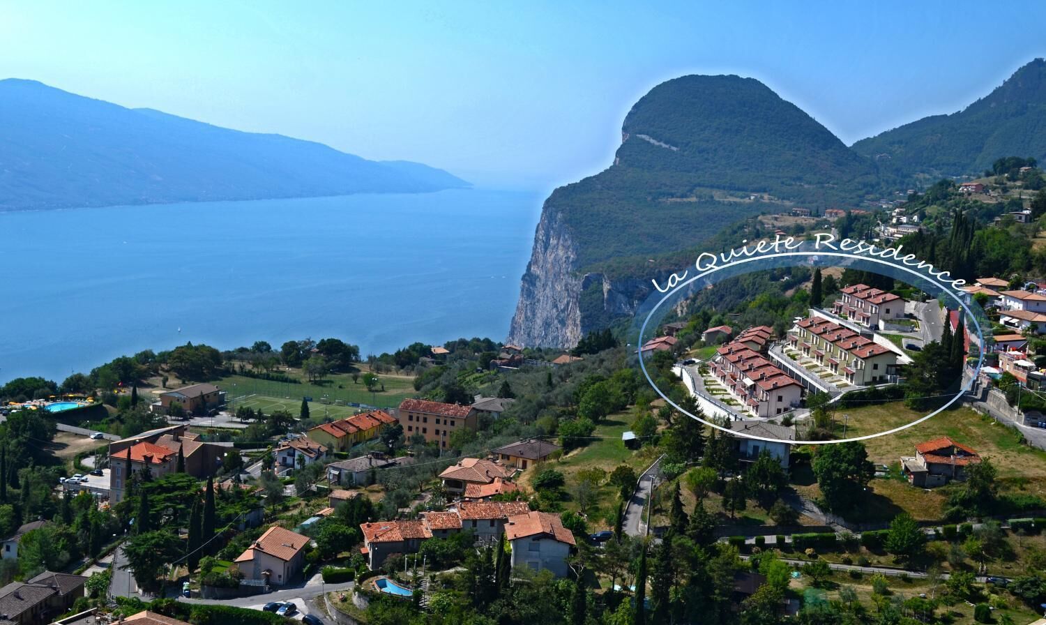 An aerial view of a coastal village with a prominent mountain in the background.
