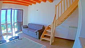 A room with a wooden staircase, a sofa, and a glass table. - La Quiete 58 Holideal (Tremosine)