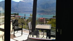 A balcony with a view of a lake and mountains. There are two chairs and a small table. - La Quiete 58 Holideal (Tremosine)