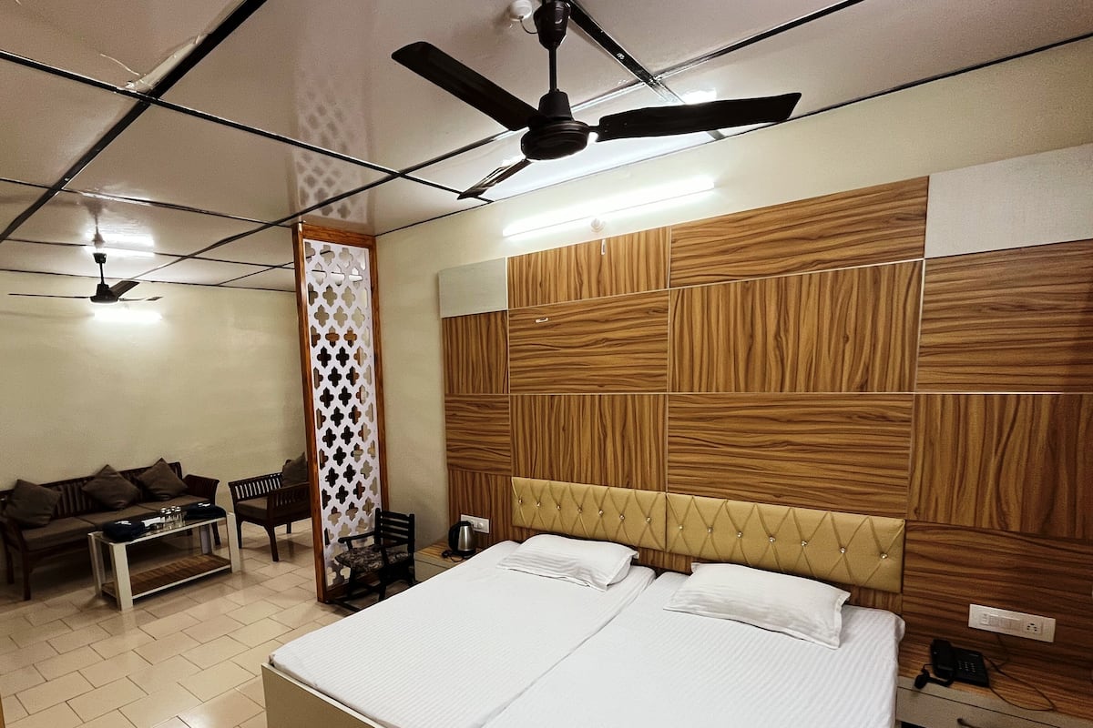 Una habitación de hotel con una cama grande, un sofá, una mesa de centro y un ventilador de techo.