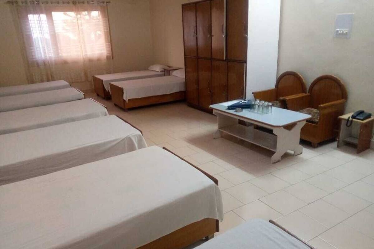 Una habitación de hotel con varias camas, un armario, una mesa y una silla.