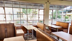 A dining area with booths and tables, large windows with metal bars, and a view of the outside.