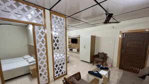 A hotel room with a bed, a wooden chair, a sofa, a small table, and a wardrobe.