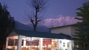 A building with large windows and a flat roof, surrounded by trees and mountains in the background.