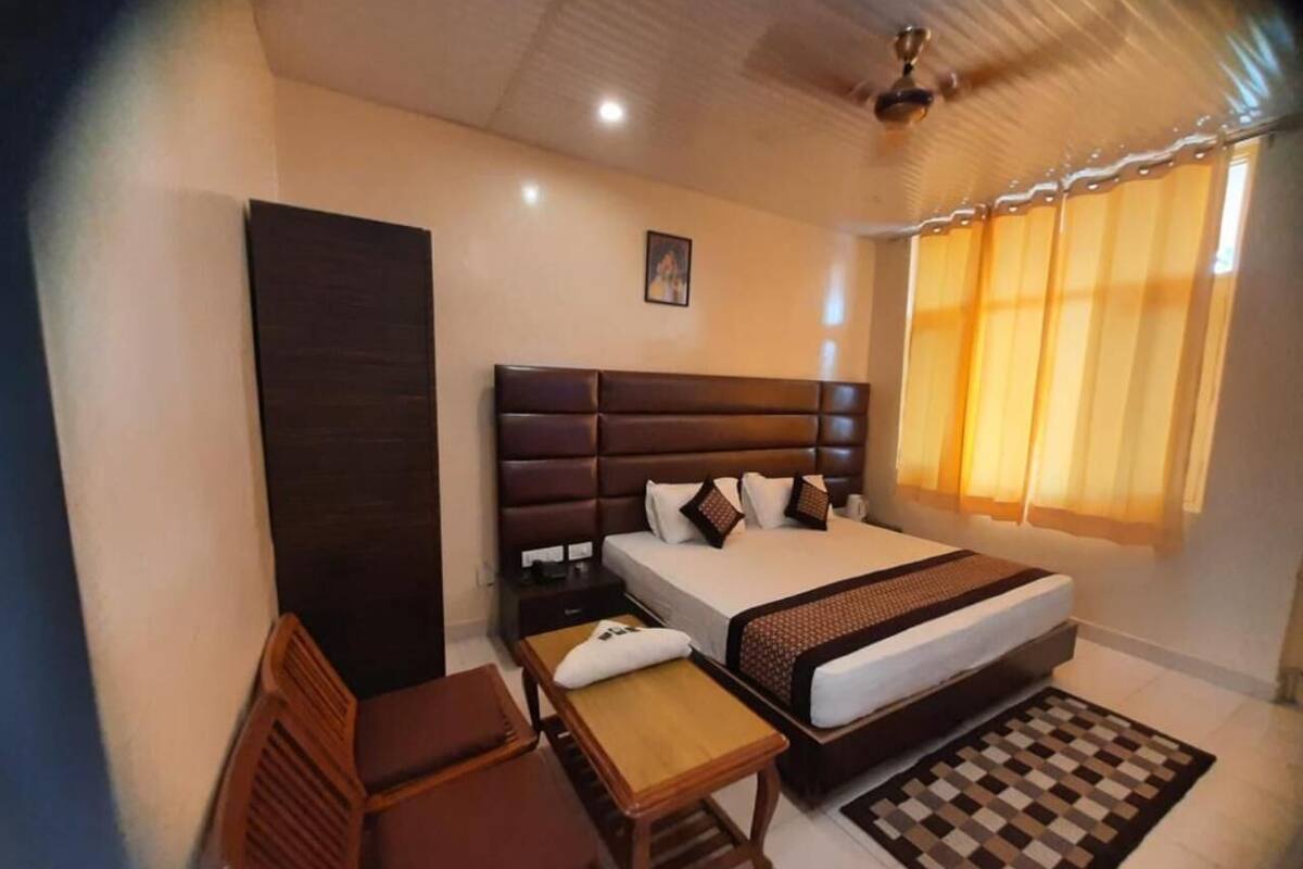 Habitación de hotel con cama, escritorio, silla, armario y ventana con cortinas.