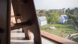 A wooden chair with a curved backrest and a cut-out design, positioned near a window overlooking a residential area with houses and greenery. - XinFu Traveler Inn (Beinan)