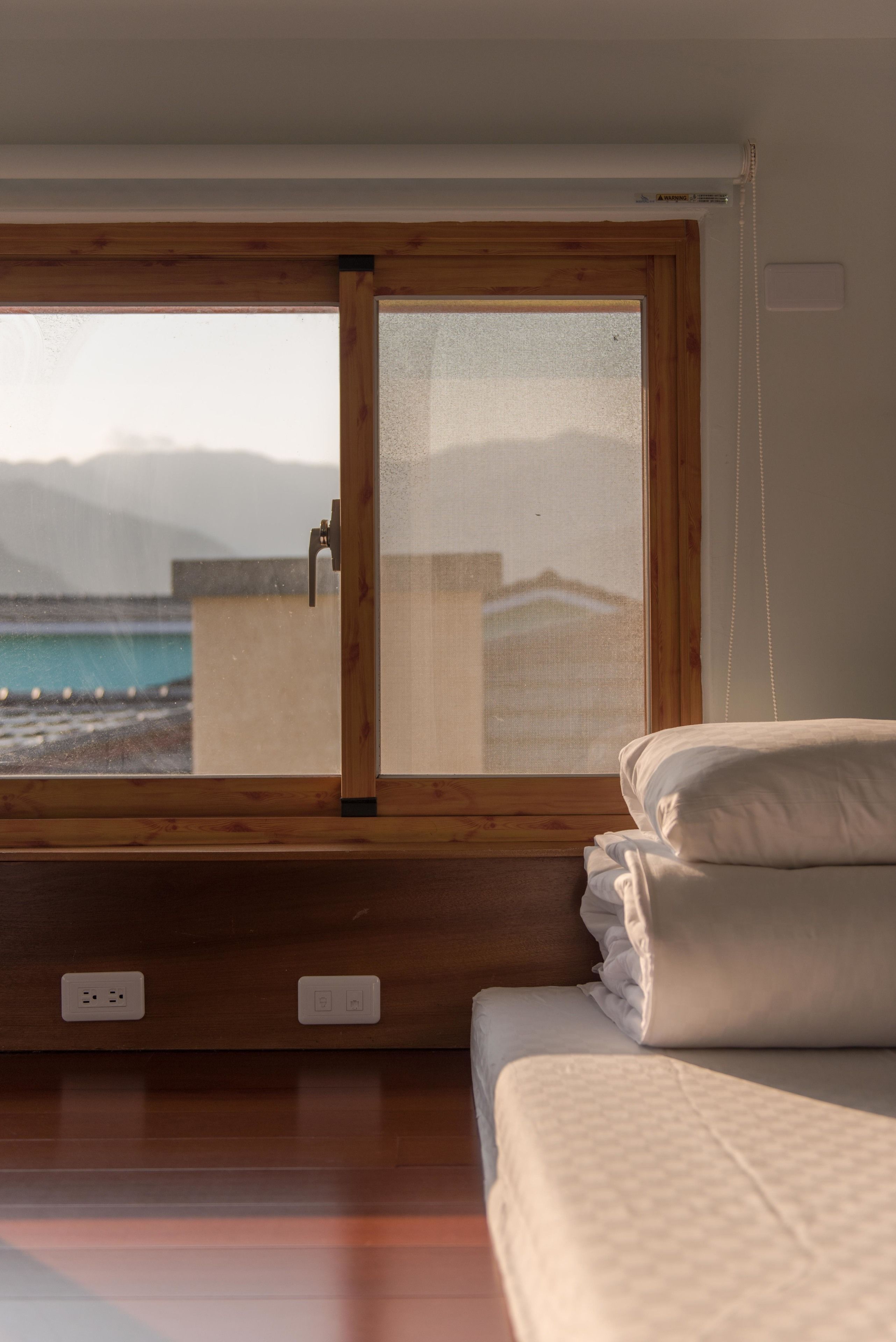 A bedroom with a large window, a bed, and a view of the sea.