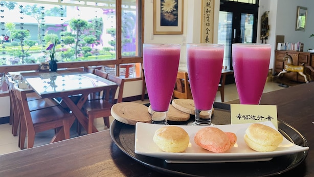 A dining area with a table set for three, featuring a tray with pink drinks and three pastries. - XinFu Traveler Inn (Beinan)