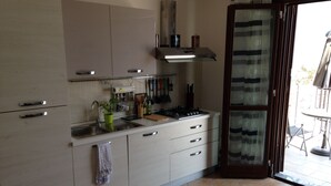 Une cuisine moderne avec des meubles blancs, une cuisinière à gaz et une fenêtre agrémentée d’un rideau à rayures.