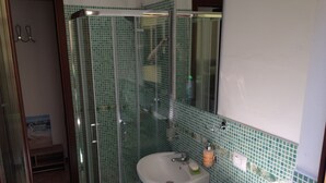 Une salle de bain avec une douche à parois de verre, un lavabo et un miroir.