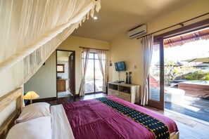 Quarto com cama, televisão, escrivaninha e vista para a área externa.