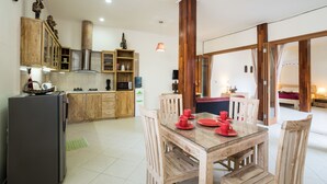 Una cocina moderna con armarios de madera, una mesa de comedor con platos rojos y un grueso pilar de madera.