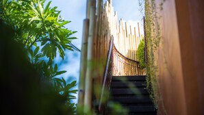 Una escalera de bambú que conduce a una estructura tradicional de madera, rodeada de exuberante follaje.