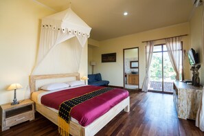 Quarto com cama de dossel, escrivaninha com televisão e vista para o exterior.