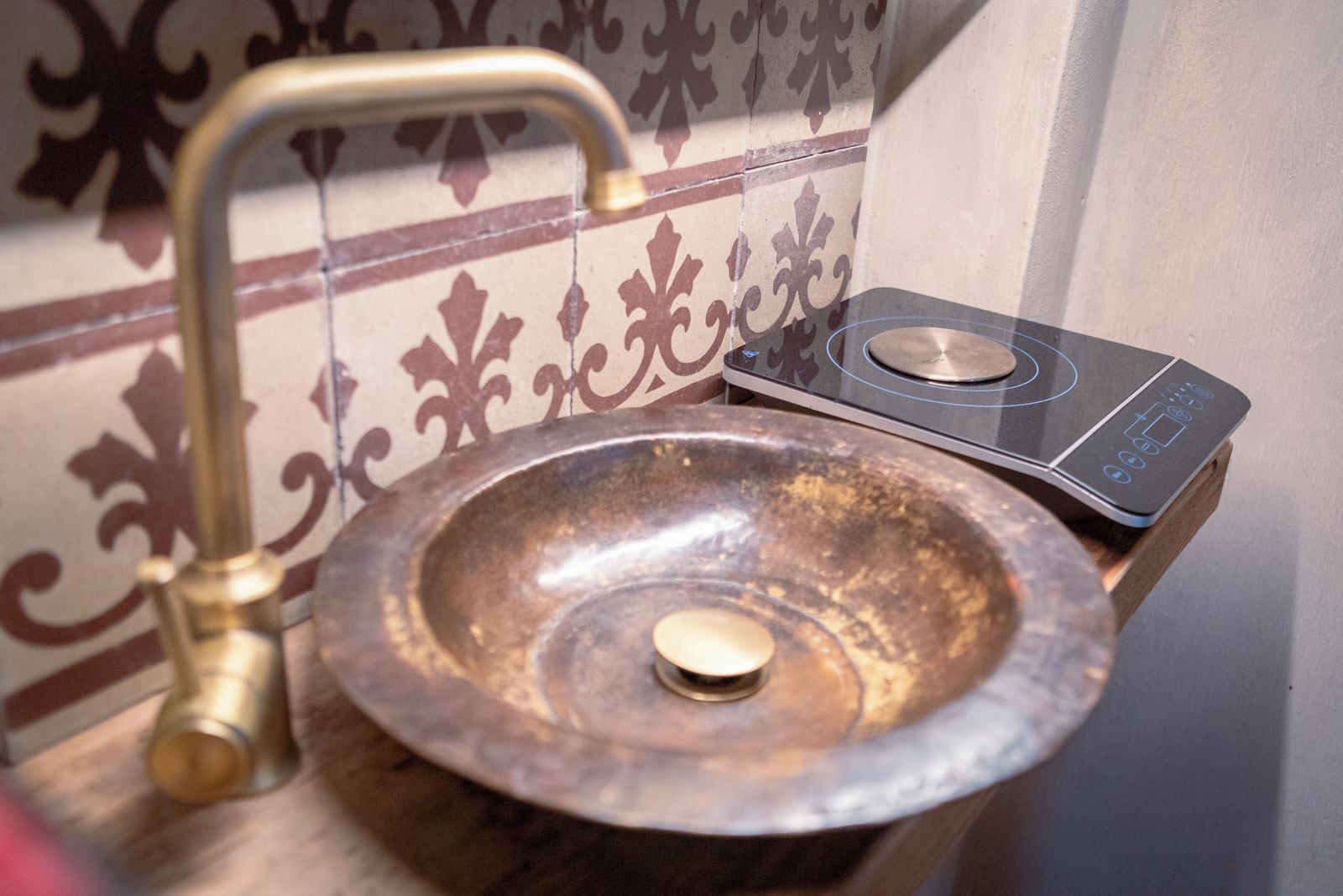 Ein Badezimmerwaschbecken mit einem Messingarmaturen und einer digitalen Waage auf einem Holzboden.