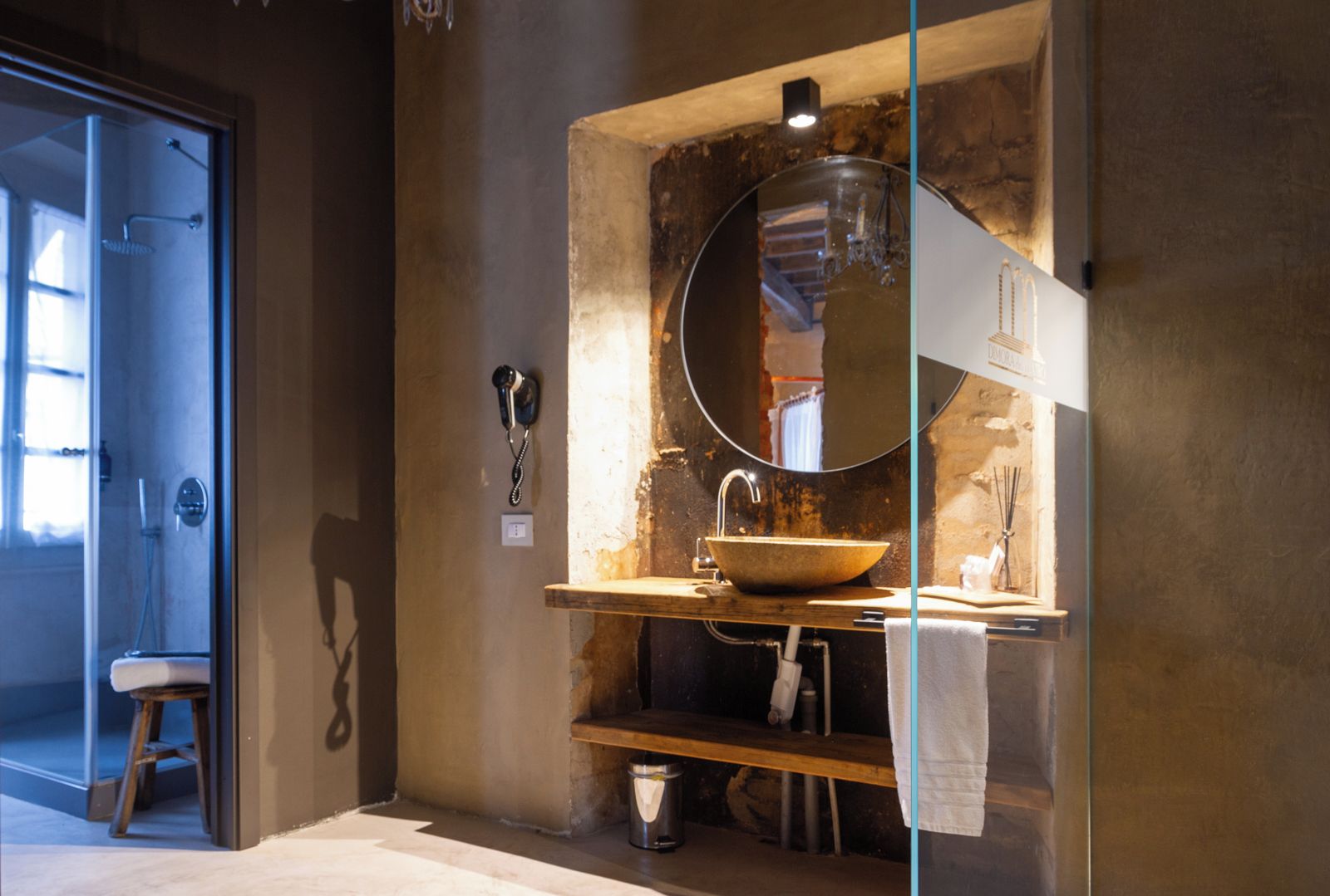 A bathroom with a large mirror, a wooden vanity, a sink, and a towel rack.
