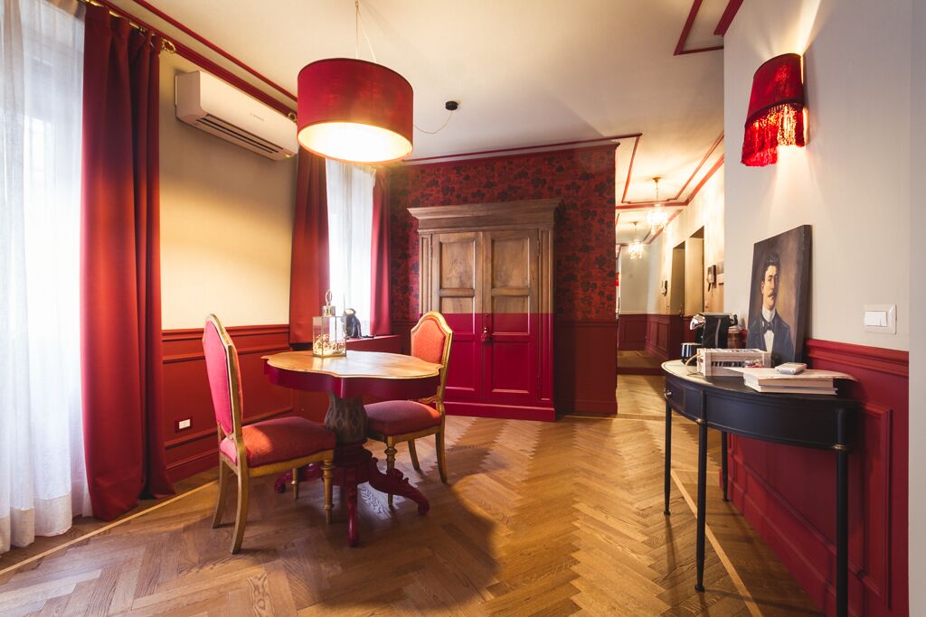 A dining area with a round table, red chairs, and a red wall.