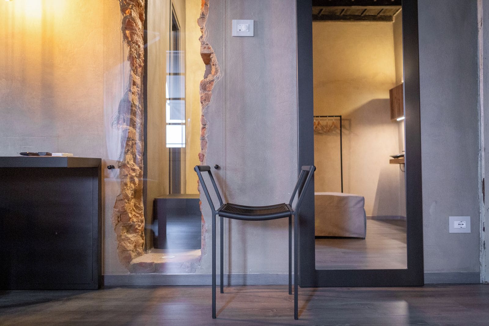 Un intérieur moderne agrémenté d’un mur en briques rustiques, d’une chaise à armature métallique et d’un bureau en bois foncé.