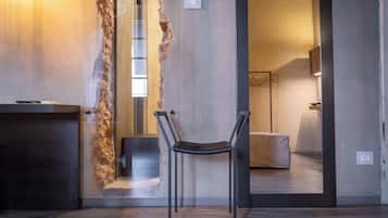A modern interior with a rustic brick wall, a metal-framed chair, and a dark wooden desk.