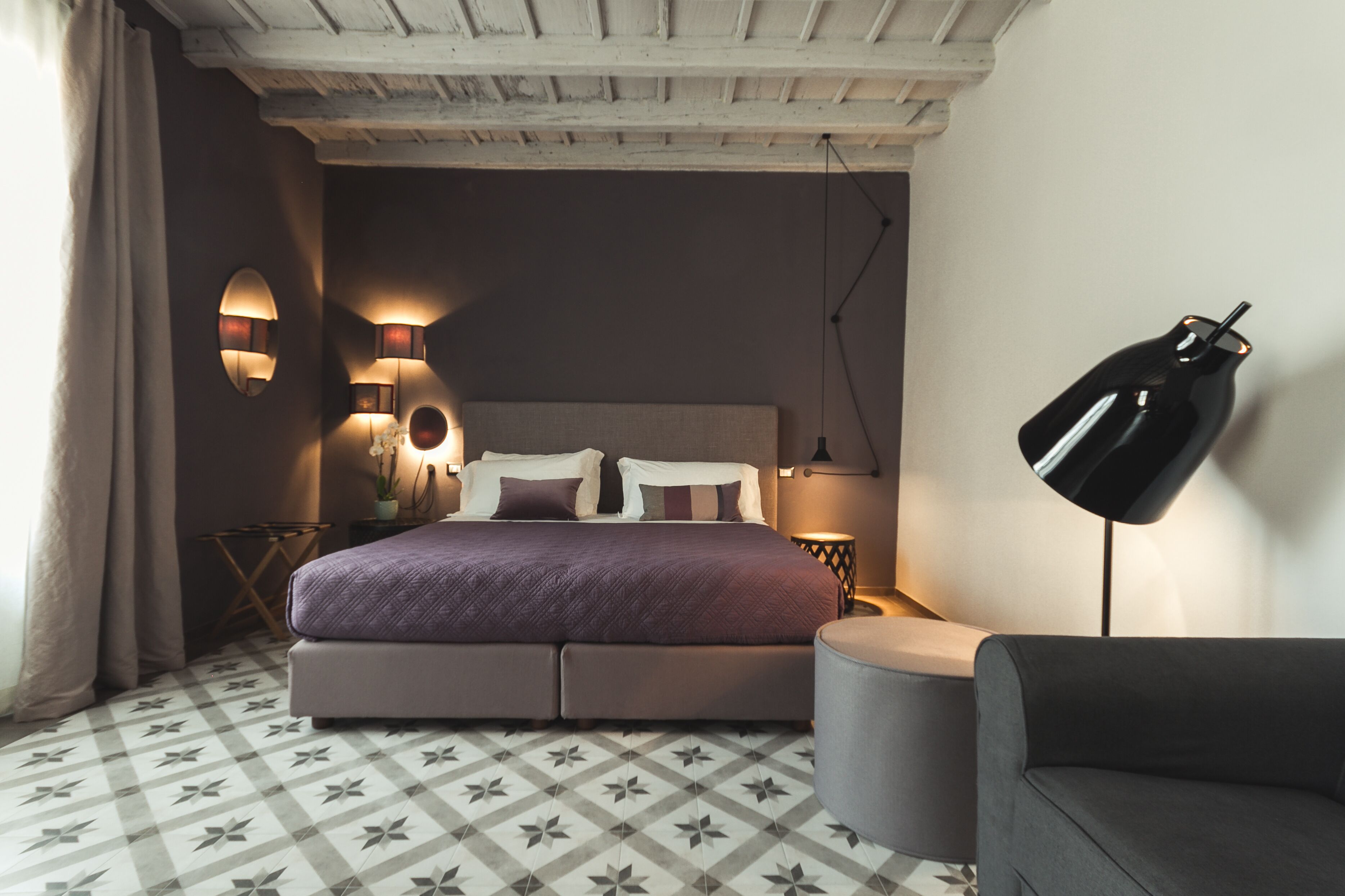A bedroom with a bed, bedside lamps, a nightstand, and a sofa.