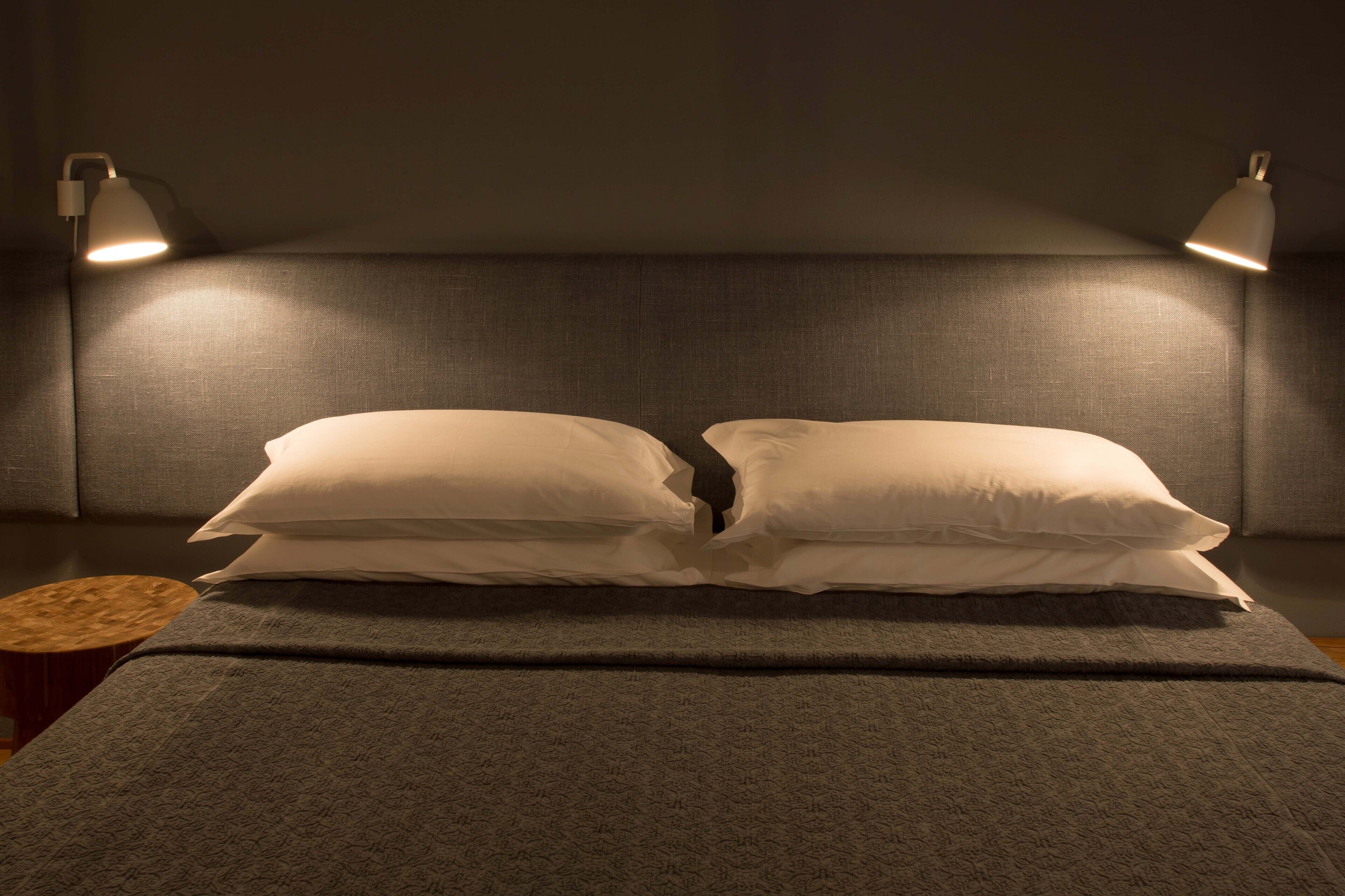 A neatly made bed with two pillows and two bedside lamps.