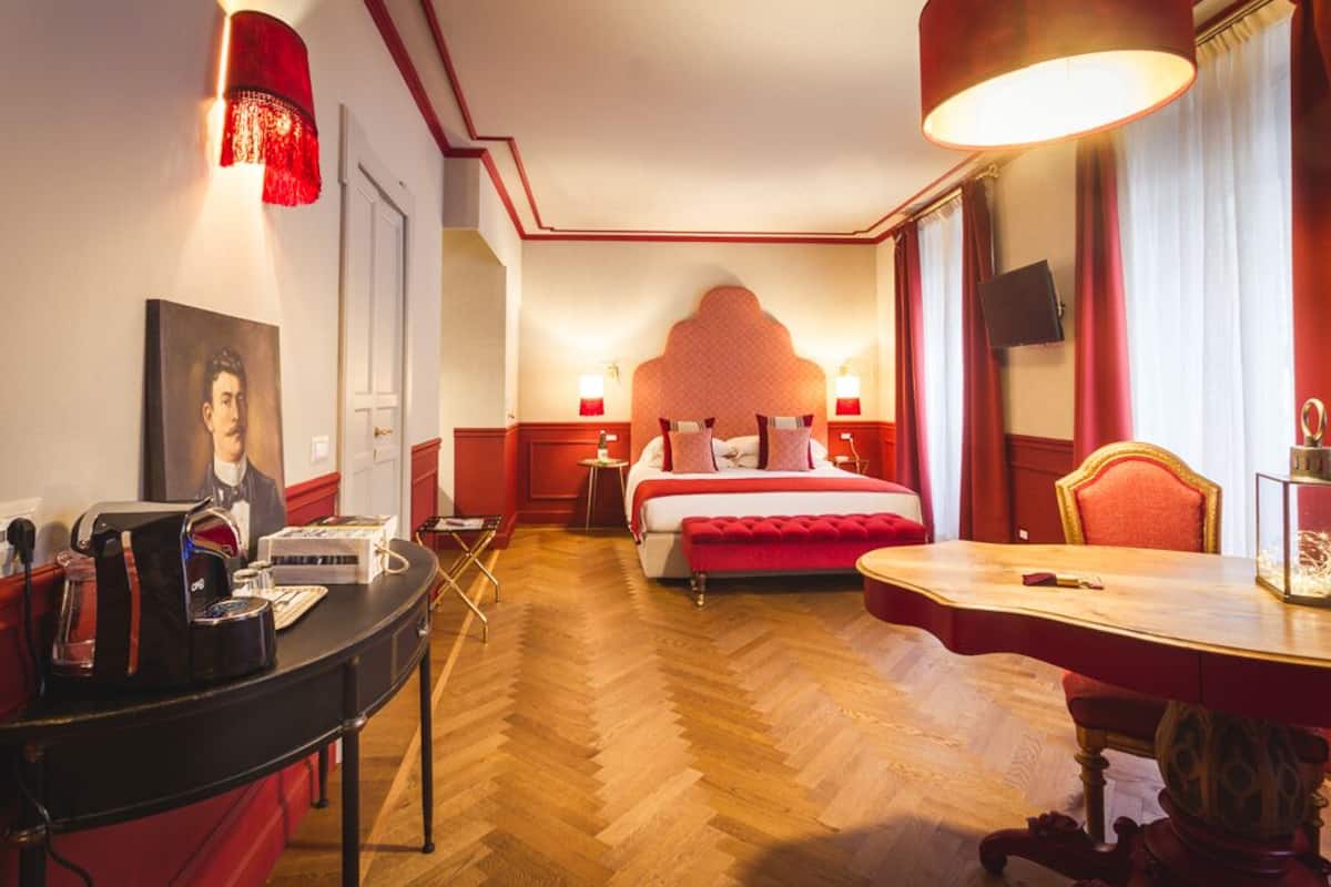 A hotel room with a bed, bedside tables, a desk, and a chair.