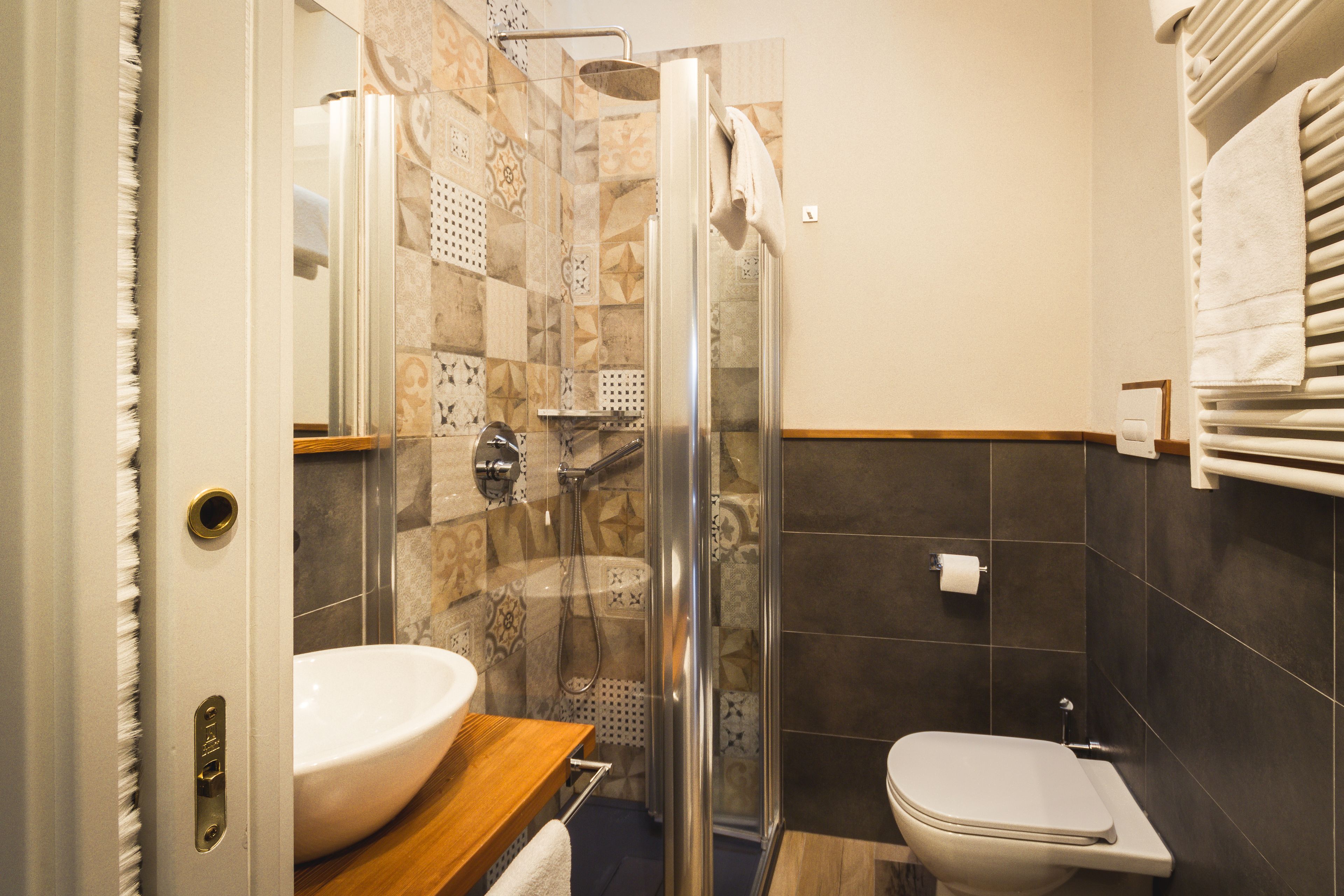 A bathroom with a glass-enclosed shower, a white sink, and a toilet.
