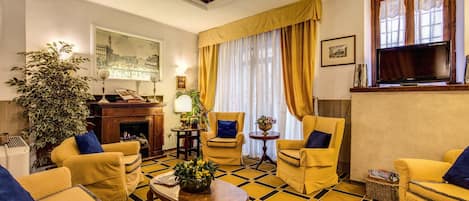 A living room with yellow sofas, a fireplace, and a large window with curtains.