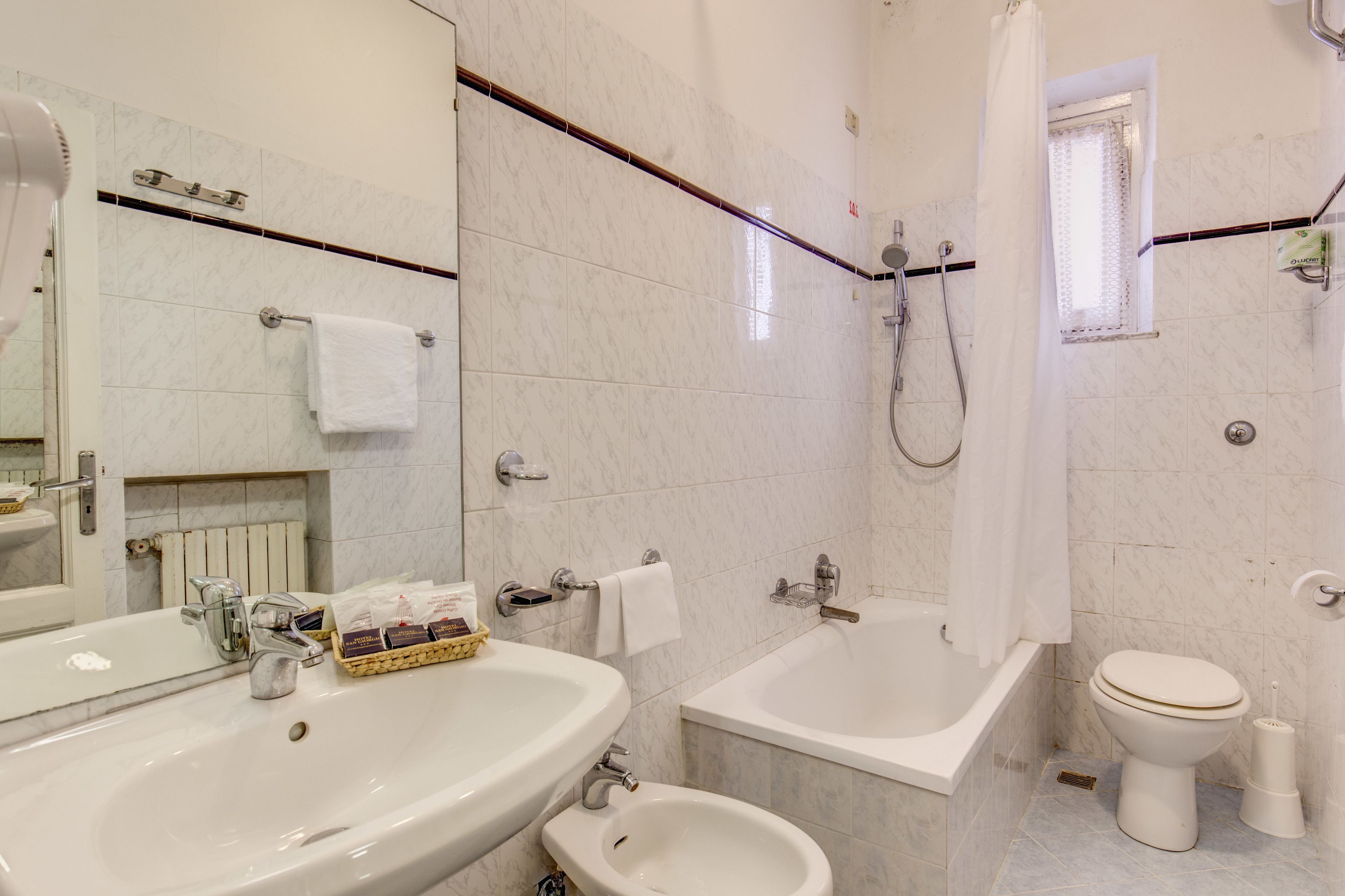 A bathroom with a sink, bidet, bathtub, and toilet.