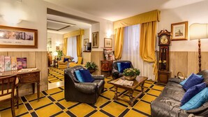 A hotel lobby with a checkered floor, leather sofas, a wooden coffee table, and a clock on the wall. - Hotel San Giorgio & Olimpic Florence (Florence)
