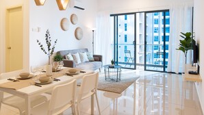 A modern living room with a dining area, large windows, and a ceiling fan. - Atlantis Residence by Stayshare Homes (Malacca City)
