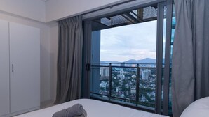 Ein Schlafzimmer mit großem Fenster, einem Bett und einem Kleiderschrank.