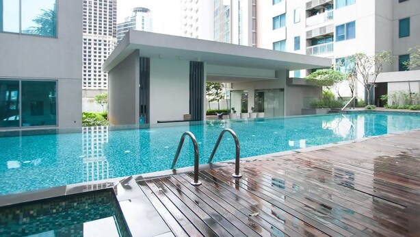 Ein moderner, überdachter Swimmingpool mit Holzterrasse, umgeben von Hochhäusern.