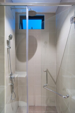 A shower with a glass door, a handheld showerhead, and a handheld shower attachment.