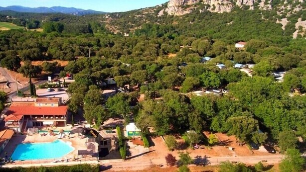 Vista aérea de un resort con piscina, varias construcciones y zonas verdes circundantes.