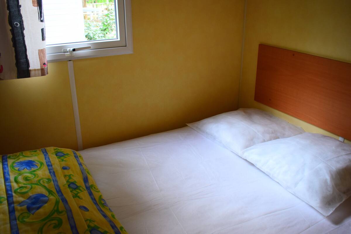 A single bed with white bedding in a room with yellow walls and a wooden headboard.
