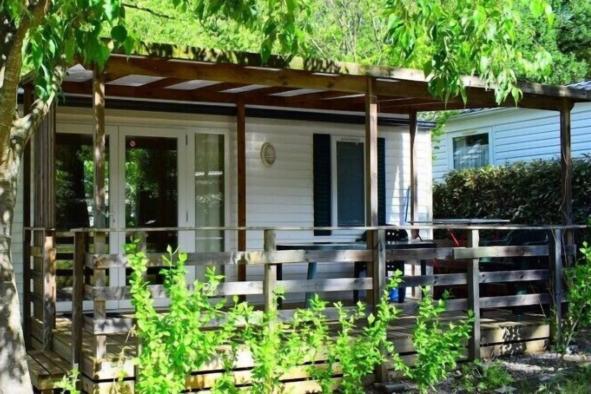 A small, single-story mobile home with a porch and a wooden fence.