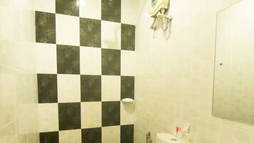 A bathroom with a checkered tile wall, a toilet, a sink, and a showerhead.