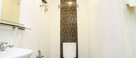 Un baño pequeño con lavamanos blanco, inodoro y zona de ducha.