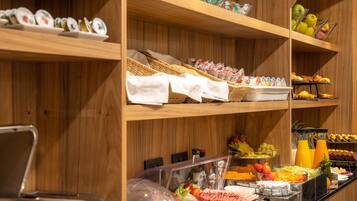 A buffet with various food items and beverages, including fruits, vegetables, and prepared dishes, displayed on wooden shelves.